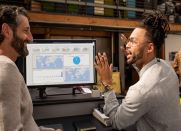 Two co-workers reviewing report dashboard on a screen