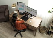 Woman working on a desk with two screens